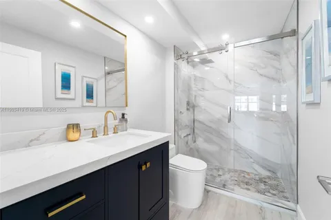 a bathroom with a sink vanity granite toilet and shower