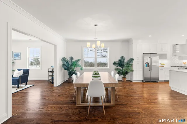 a kitchen with stainless steel appliances kitchen island granite countertop a stove a sink a dining table and chairs with wooden floor