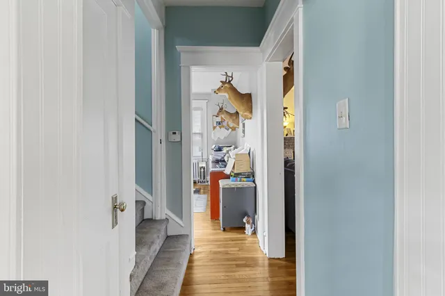 a view of a hallway with wooden floor and a bathroom