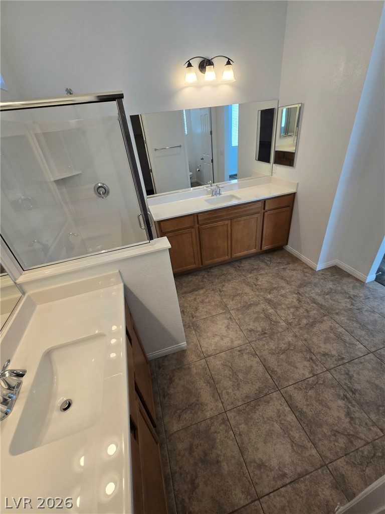 4748 Ritual Street North Las Vegas, NV 89031 - Photo 15 of 31 A well-appointed bath features dual vanities and a glass-enclosed shower, offering practical elegance.