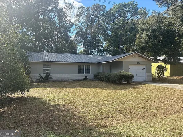 a front view of house with yard and trees in the background
