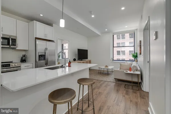a living room with furniture a flat screen tv and kitchen view