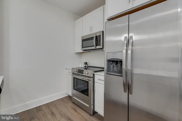a kitchen with stainless steel appliances wooden floor and a refrigerator