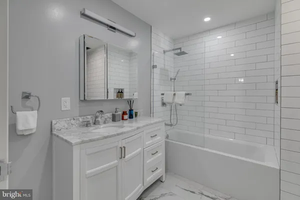 a bathroom with a tub sink vanity granite and a mirror