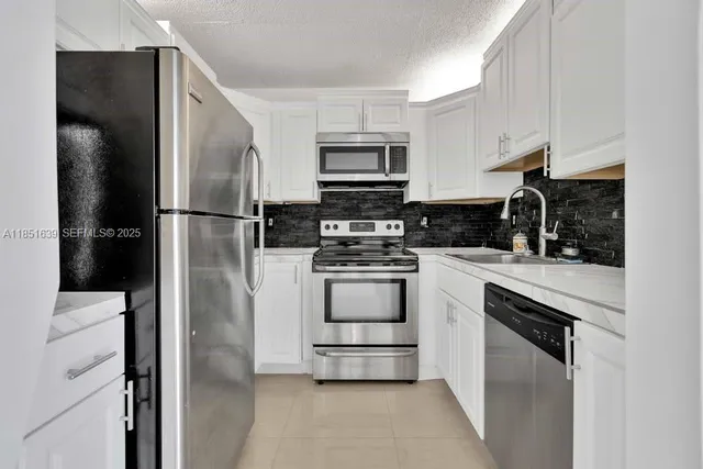 a kitchen with white cabinets and stainless steel appliances