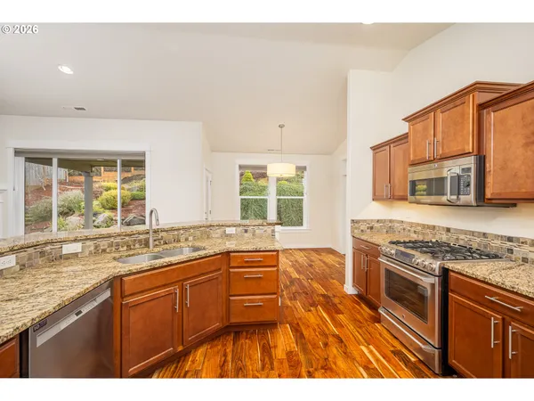 a kitchen with stainless steel appliances granite countertop a stove a sink and a granite counter tops with white cabinets