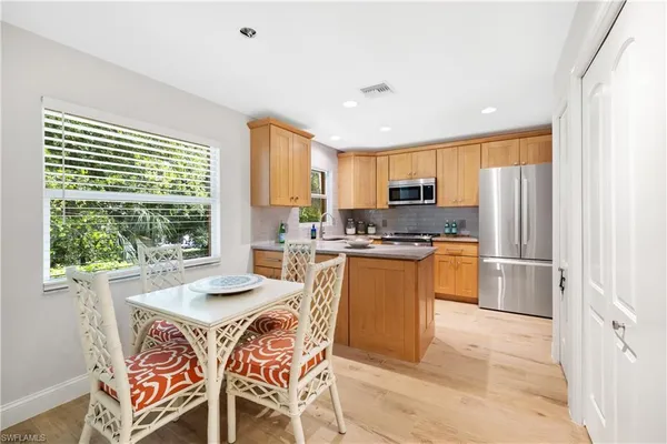 a kitchen with a refrigerator a stove a sink dishwasher and a dining table with wooden floor