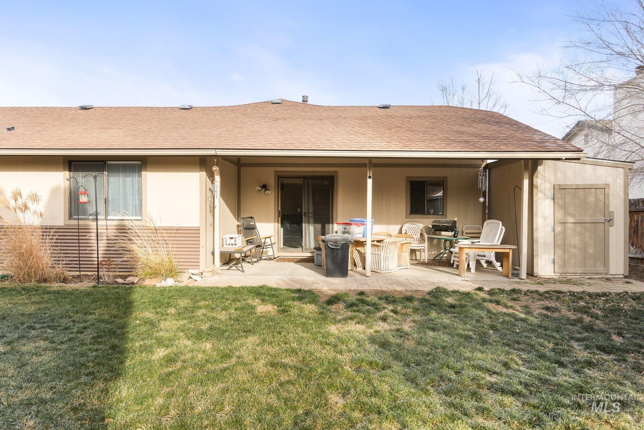 7567 Sundance Drive Boise, ID 83709 - Photo 19 of 21 Back of house with a lawn, roof with shingles, a patio area, and a storage shed