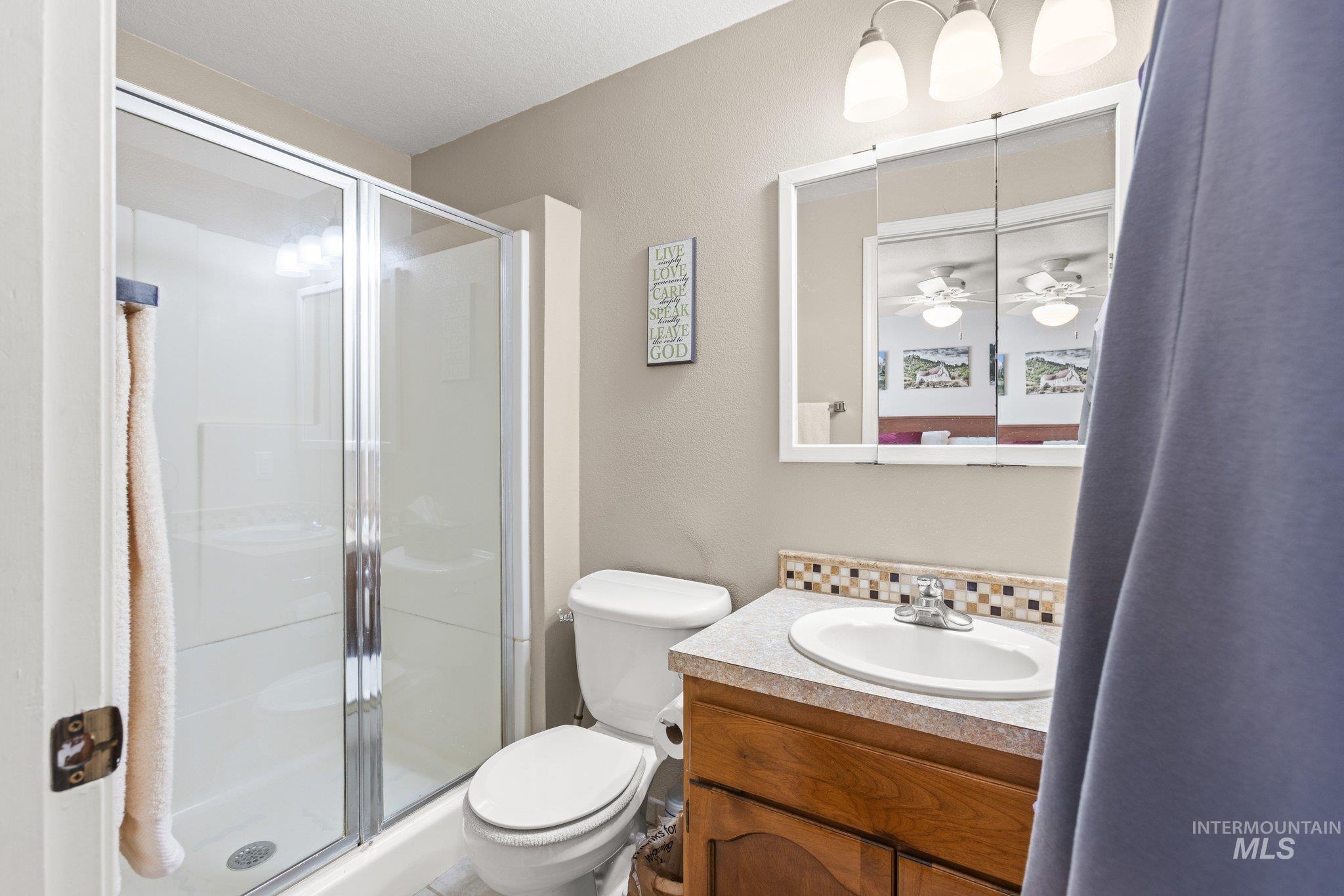 7567 Sundance Drive Boise, ID 83709 - Photo 8 of 21 Bathroom with a stall shower, vanity, tasteful backsplash, and a textured wall