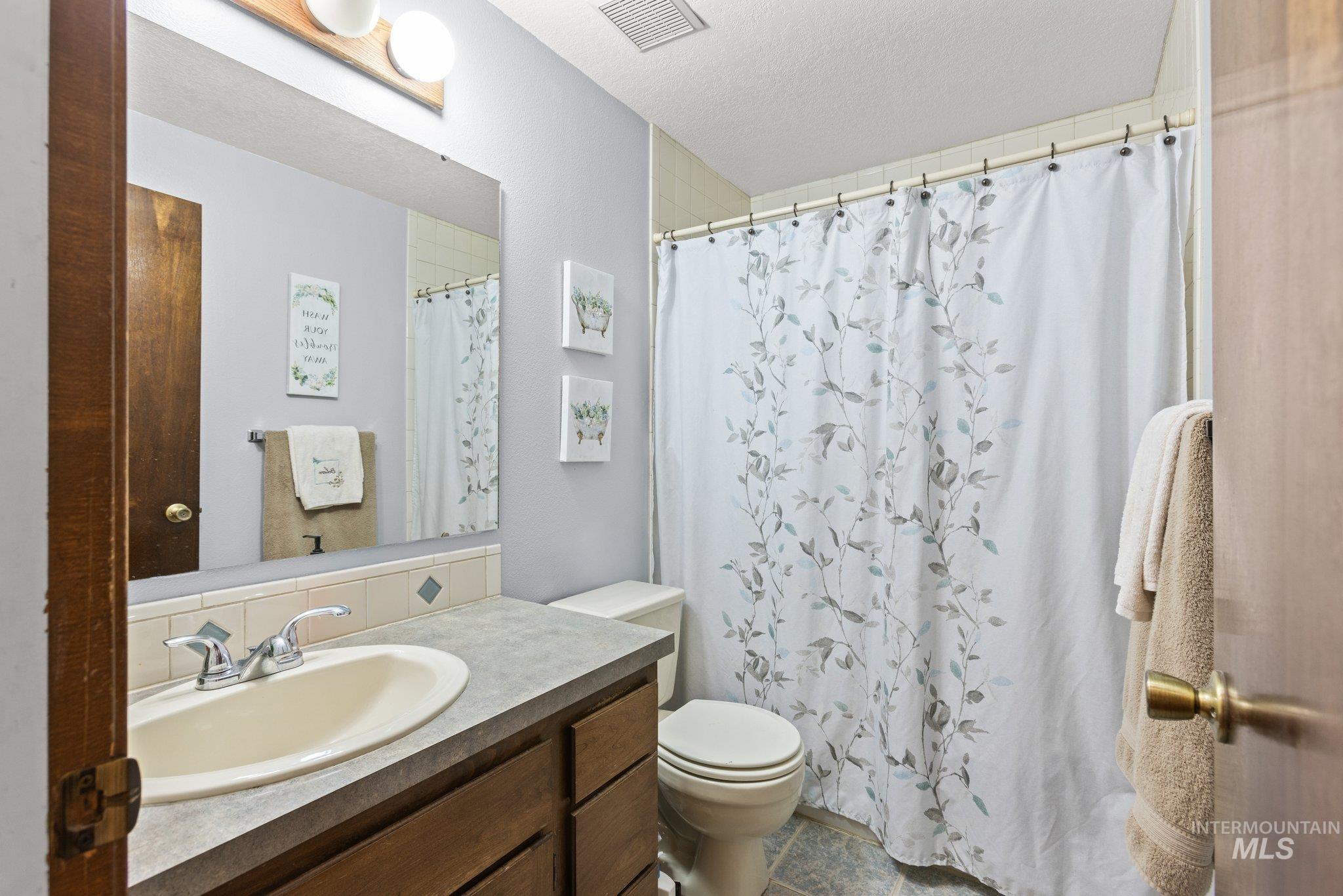 7567 Sundance Drive Boise, ID 83709 - Photo 10 of 21 Bathroom with vanity, curtained shower, and a textured ceiling