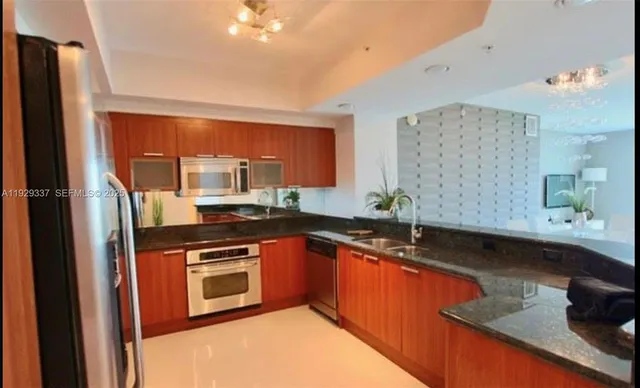 a kitchen with stainless steel appliances granite countertop a sink and a refrigerator