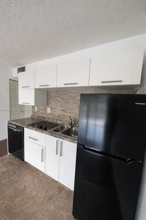 a kitchen with a refrigerator and white cabinets