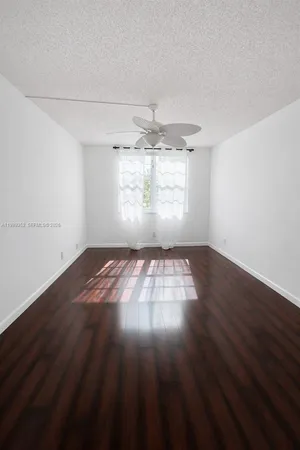 an empty room with wooden floor chandelier fan and windows