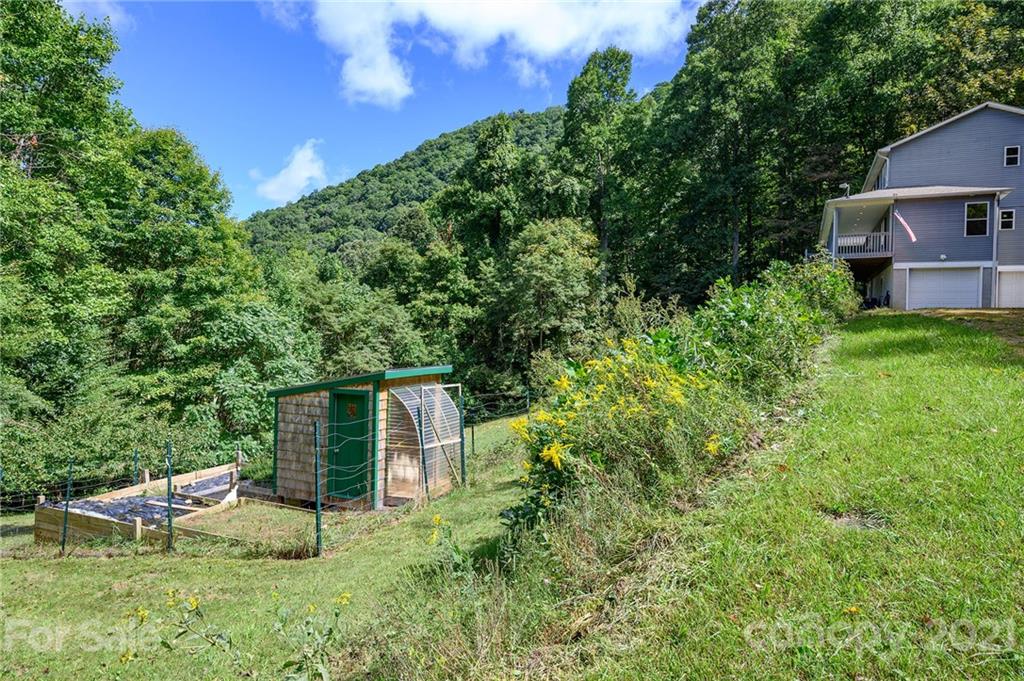 1747 Secluded Valley Road Marshall, NC 28753 - Photo 25 of 33 a backyard of a house with table and chairs plants and large tree