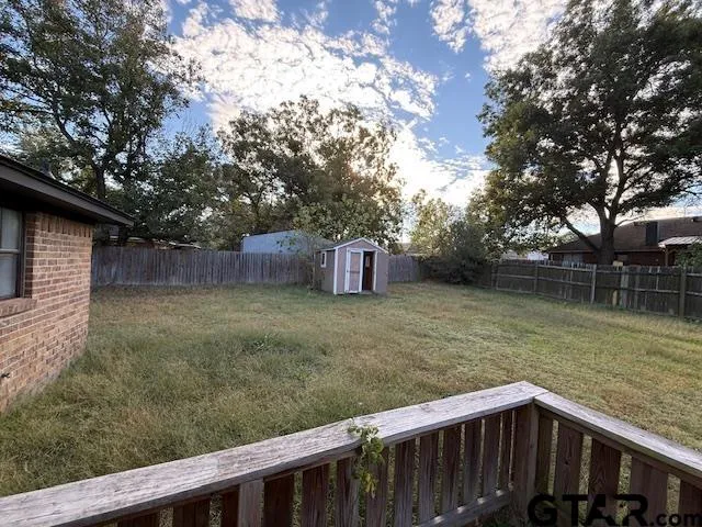 a view of a backyard with large trees and wooden fence