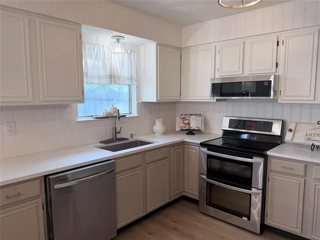 a kitchen with stainless steel appliances a sink cabinets and a wooden floor