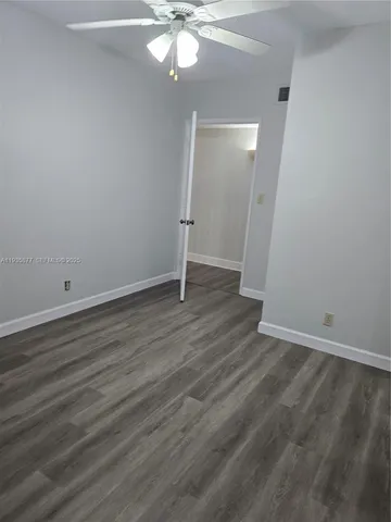 an empty room with wooden floor and fan