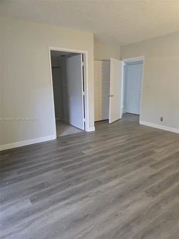 a view of an empty room with wooden floor and closet