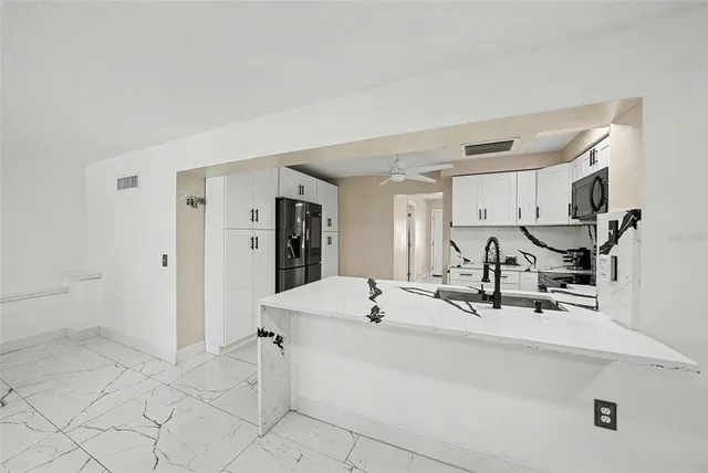 a room with a sink a counter and chairs