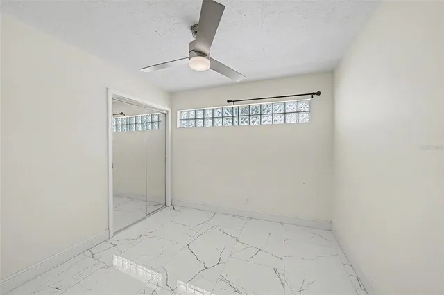 an empty room with a ceiling fan and carpet