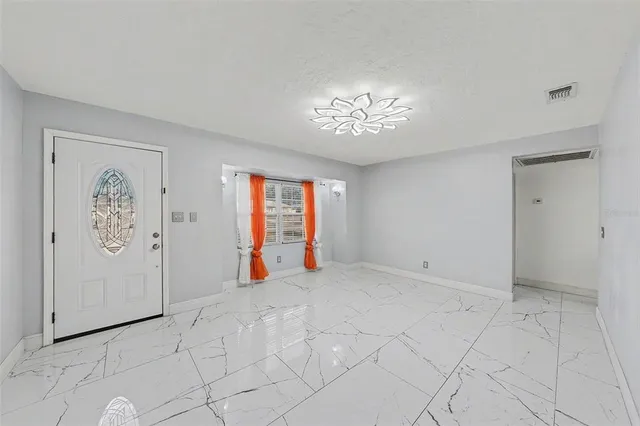 a view of a livingroom with a chandelier fan and windows