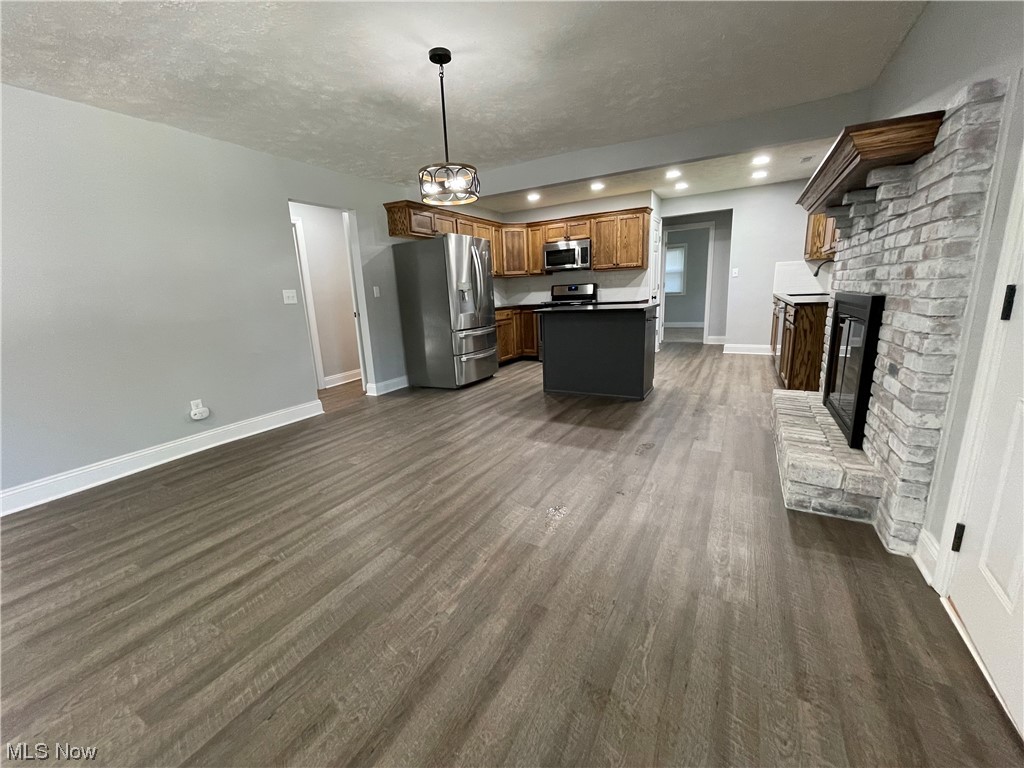 1857 Sterling Road Madison, OH 44057 - Photo 11 of 33 Kitchen with appliances with stainless steel finishes, light hardwood floors, a fireplace, and a textured ceiling