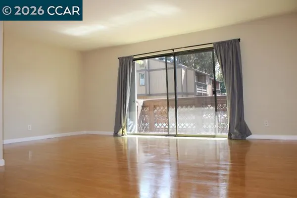 a view of an empty room with wooden floor and a window