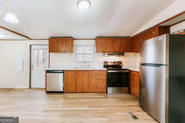 a kitchen with granite countertop a refrigerator stove top oven and sink
