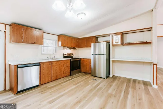 a kitchen with a refrigerator a stove and a wooden floor