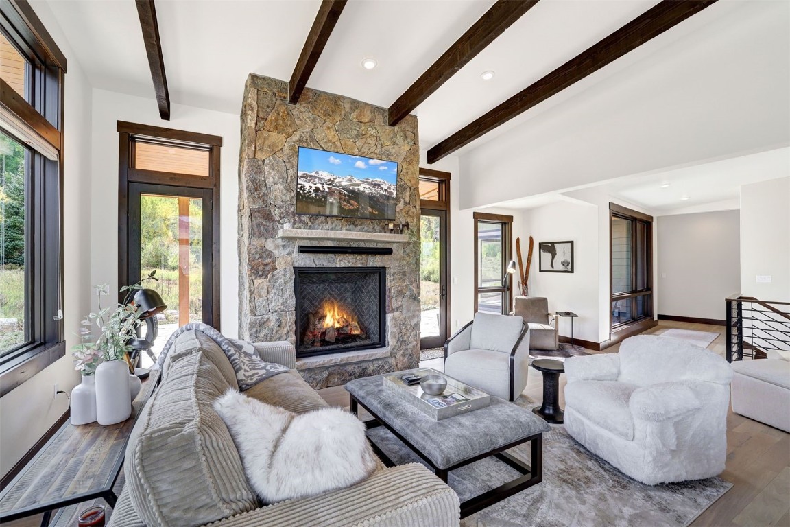 160 Vendette Road Silverthorne, CO 80498 - Photo 12 of 50 Living area featuring wood finished floors, beam ceiling, and a stone fireplace