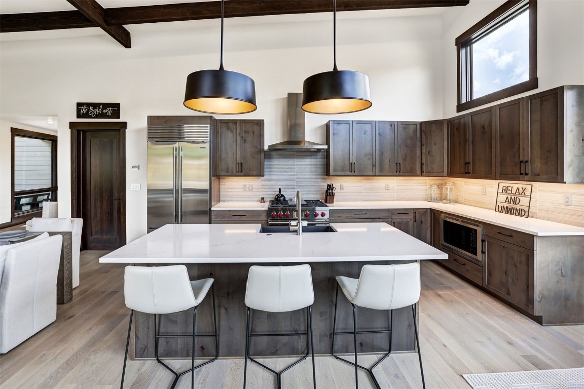 160 Vendette Road Silverthorne, CO 80498 - Photo 17 of 50 Kitchen featuring beam ceiling, a kitchen breakfast bar, dark brown cabinets, built in appliances, and a kitchen island with sink