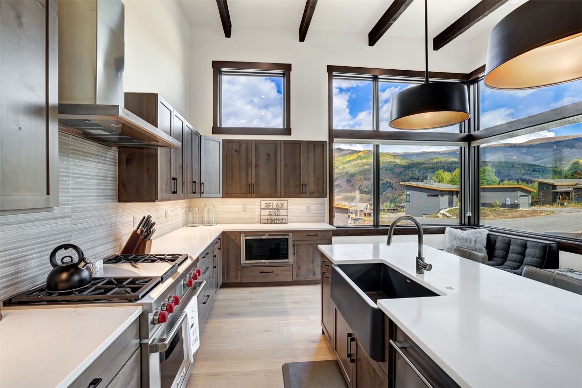 160 Vendette Road Silverthorne, CO 80498 - Photo 19 of 50 Kitchen with appliances with stainless steel finishes, wall chimney range hood, pendant lighting, beamed ceiling, and light wood-style flooring