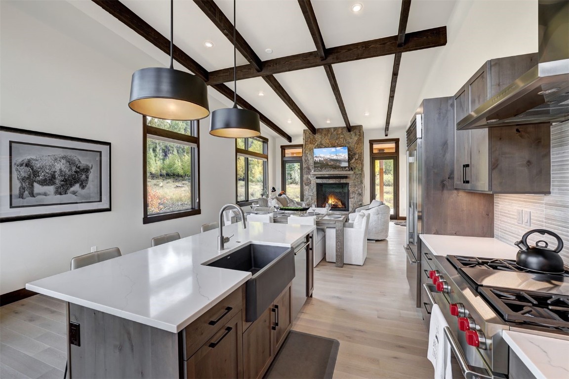 160 Vendette Road Silverthorne, CO 80498 - Photo 20 of 50 Kitchen with a breakfast bar, beamed ceiling, a center island with sink, light wood-type flooring, and wall chimney exhaust hood