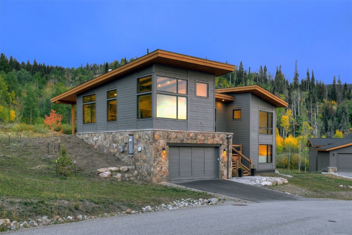 160 Vendette Road Silverthorne, CO 80498 - Photo 4 of 50 Modern home featuring stone siding, driveway, an attached garage, and a wooded view