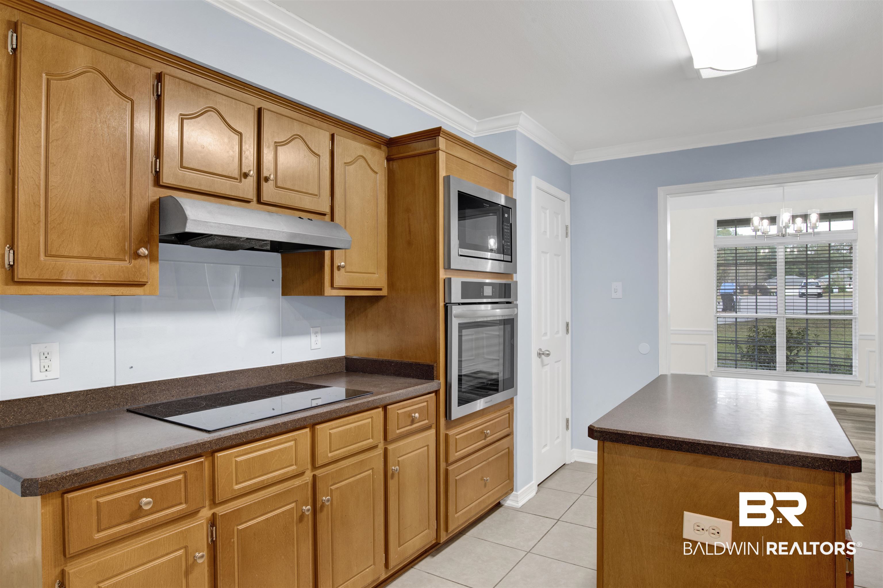 9534 Labrador Run North Mobile, AL 36695 - Photo 8 of 30 Kitchen featuring stainless steel appliances, crown molding, brown cabinetry, under cabinet range hood, and a center island