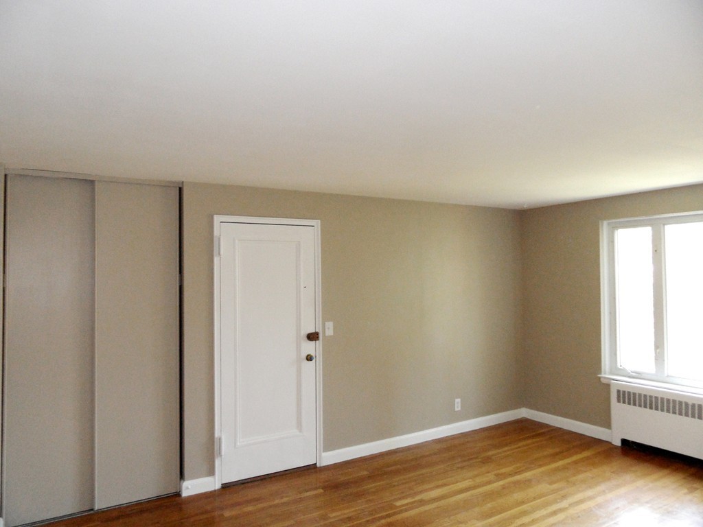 128 Beaconsfield Road, Unit 5 Brookline, MA 02445 - Photo 4 of 18 an empty room with wooden floor and windows