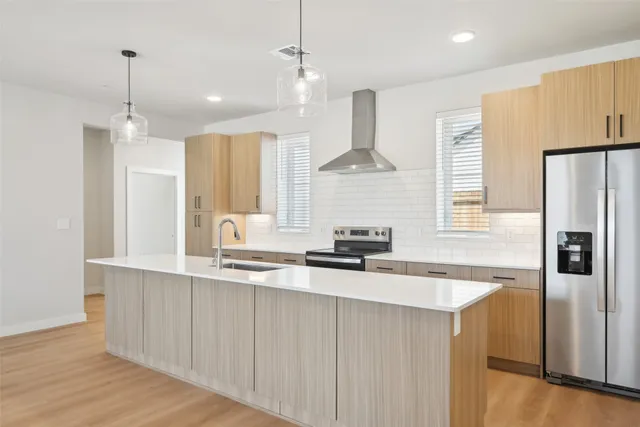 a kitchen with stainless steel appliances a sink a refrigerator a center island and cabinets