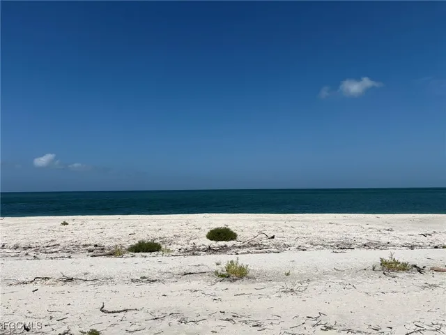 a kitchen with stainless steel appliances kitchen island granite countertop a stove a refrigerator a dining table and chairs with white cabinets