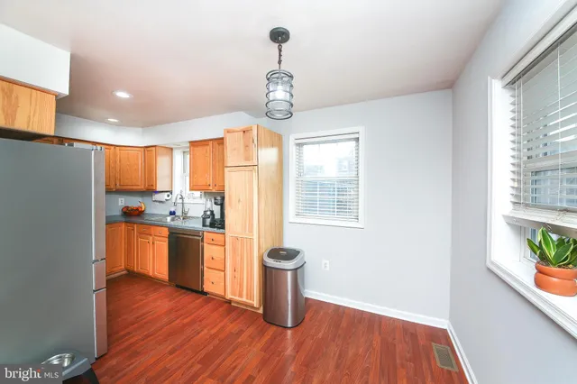 a kitchen with stainless steel appliances a wooden floor a stove a sink a refrigerator and wooden floor