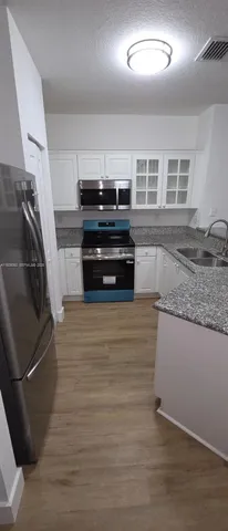 a kitchen with granite countertop a stove and a refrigerator