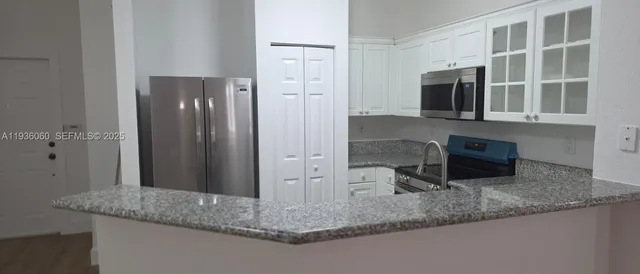 a kitchen with stainless steel appliances granite countertop a refrigerator and a granite counter tops