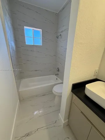 a bathroom with a granite countertop sink and a toilet