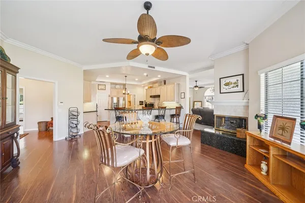 a dining room with wooden floor a chandelier fan a glass table and chairs