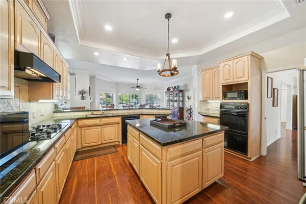 a kitchen with stainless steel appliances granite countertop a refrigerator a sink dishwasher a stove and white countertops with wooden floor