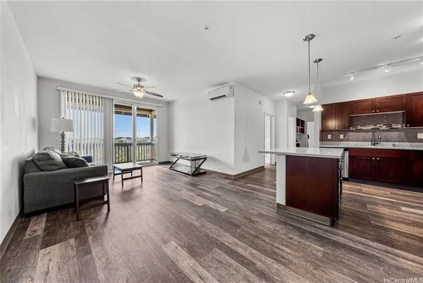 a living room with stainless steel appliances kitchen island granite countertop furniture a rug a kitchen and a wooden floor