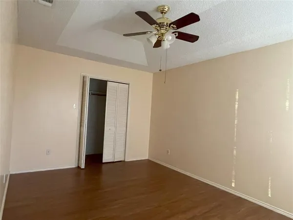 an empty room with wooden floor and a ceiling fan