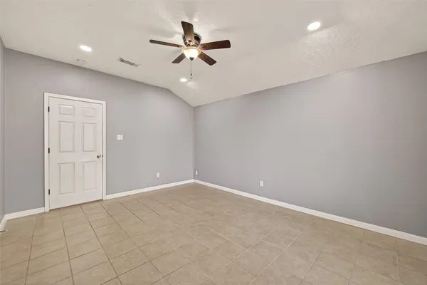 an empty room with a chandelier fan and windows
