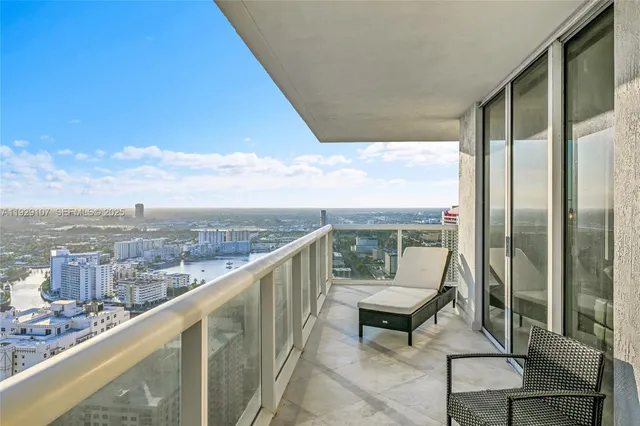 a view of a city from a balcony with a couple of chairs