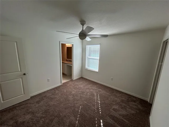 an empty room with windows and ceiling fan