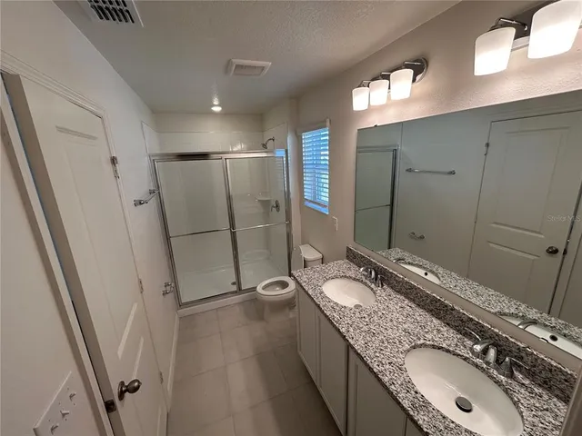 a bathroom with a granite countertop double vanity sink and mirror